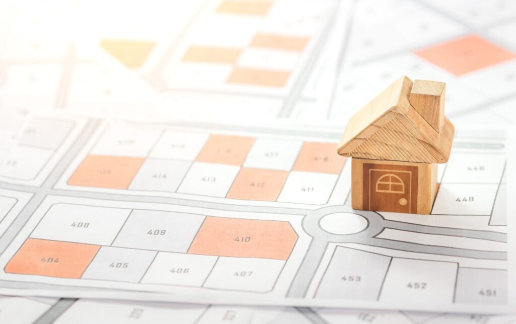 区画整理された地図の上に置かれた木製のミニチュアハウス。