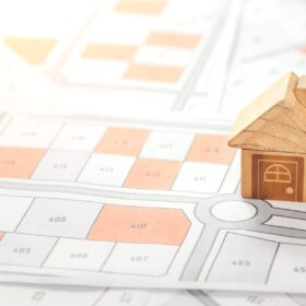 区画整理された地図の上に置かれた木製のミニチュアハウス。