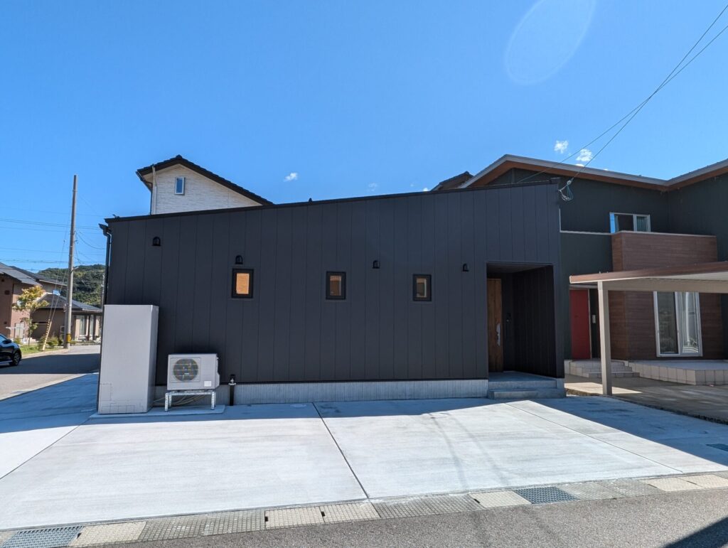 青空の下、黒いガルバリウム鋼板の外壁が特徴的なモダンな建売住宅の外観。