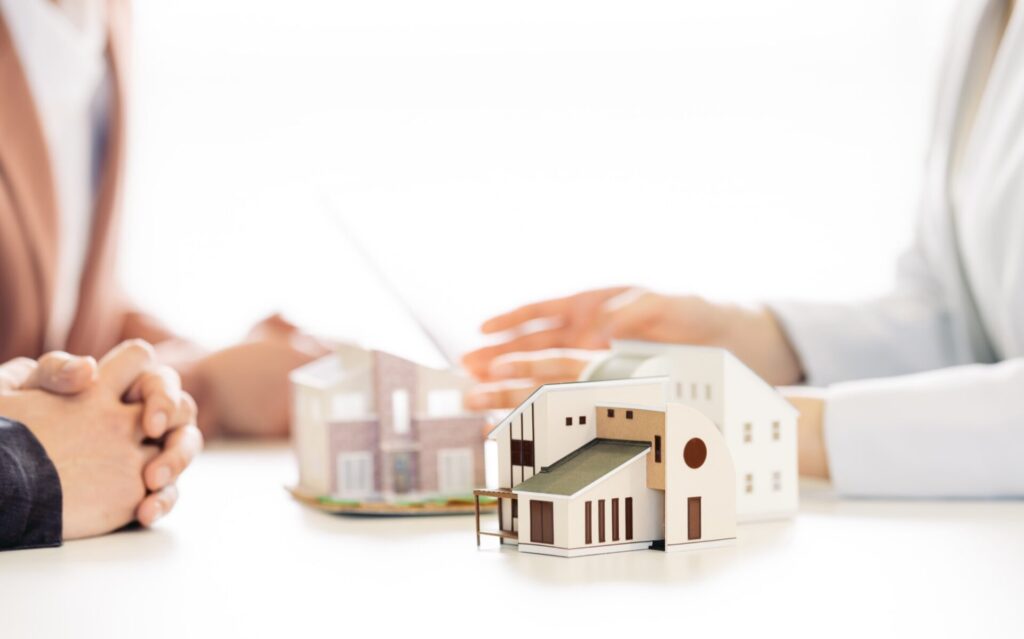 家の模型と建売住宅を悩んでいる夫婦とスタッフ